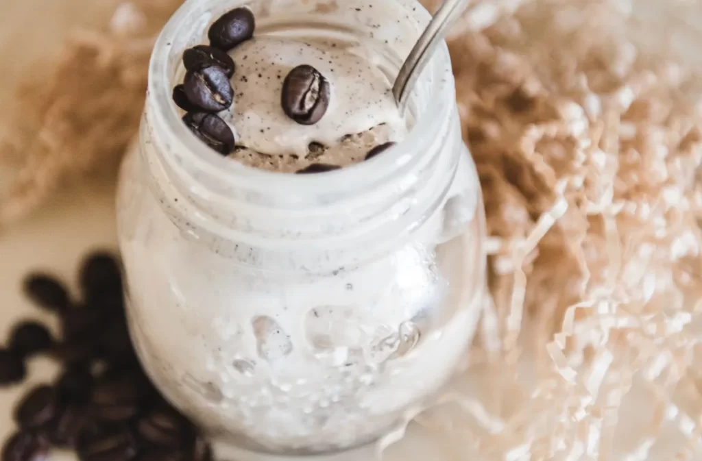 Close-up of whipped maple iced coffee with coffee beans.